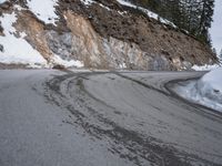 a steep cliff with a sloped off section on the side next to it, has snow piled around it