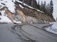 a steep cliff with a sloped off section on the side next to it, has snow piled around it