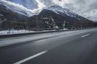 motion blurs the road as the vehicle makes its way down the mountain road with snow