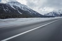 motion blurs the road as the vehicle makes its way down the mountain road with snow