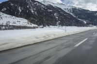 motion blurs the road as the vehicle makes its way down the mountain road with snow