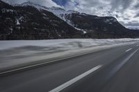 motion blurs the road as the vehicle makes its way down the mountain road with snow