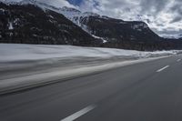 motion blurs the road as the vehicle makes its way down the mountain road with snow