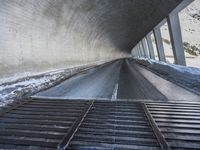 a highway is in the middle of a big long tunnel with snow on it with a bench