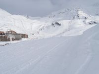 a skier going down a snowy slope by an alpine resort in winter attire with skis and poles