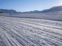 the skier is enjoying his trip down the mountain range snow tracks and mountains are visible in the background