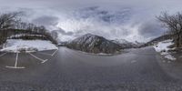 a panoramic view of snow covered mountain ranges and a winding street and pavement