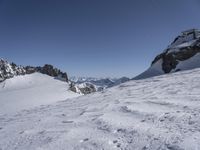 a person on skis on a slope above the mountains, surrounded by snowy land and rocks