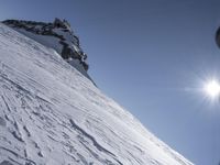 man in ski gear is going down a steep mountain, with snowboard and gear