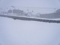 a person riding a snow board next to power lines covered in snow near buildings and cablecars