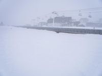 a person riding a snow board next to power lines covered in snow near buildings and cablecars