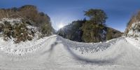 a man is snowboarding on a wide snowy mountain road under a bright sun light