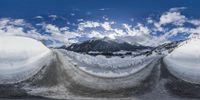 snow covered road with a view of a snowy mountain in the background and clouds overhead