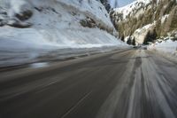 a car on the road is covered in snow as it moves toward the camera and speeds up