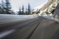 a car on the road is covered in snow as it moves toward the camera and speeds up