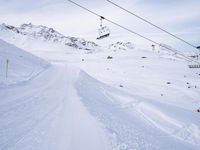 snow covered slope in the middle of a ski area as people ski on it near ski lift