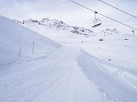 snow covered slope in the middle of a ski area as people ski on it near ski lift