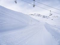 snow covered slope in the middle of a ski area as people ski on it near ski lift