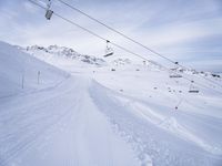 snow covered slope in the middle of a ski area as people ski on it near ski lift