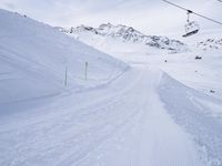 snow covered slope in the middle of a ski area as people ski on it near ski lift