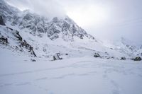 a person skiing down the side of a snowy hill with mountains in the back ground