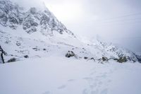 a person skiing down the side of a snowy hill with mountains in the back ground