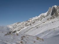 a person on skis walks along a snow covered mountain range with many snow covered mountains