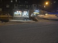 a snow covered street with a building and some stairs in the background at night time