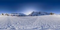 skiers in a group on the top of a slope at a resort with snow covered mountains