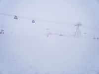 the skiers are moving down the ski slope as snow begins to fall and fog covers them