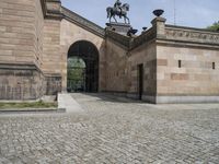 the outside entrance to the building with the statue of a man on a horse is near a wall