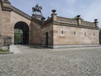 the outside entrance to the building with the statue of a man on a horse is near a wall