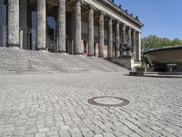 the square of a cobblestone street that leads to a building with a dome like structure