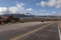 a car that is sitting in the road with mountains behind it for view of another vehicle