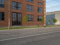 an empty street in front of a large red brick building on the other side of the road is a street light that has a line for motorists