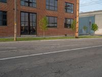 an empty street in front of a large red brick building on the other side of the road is a street light that has a line for motorists