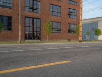 an empty street in front of a large red brick building on the other side of the road is a street light that has a line for motorists