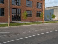 an empty street in front of a large red brick building on the other side of the road is a street light that has a line for motorists