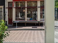 an outside window of a store on a street corner with tables and benches outside the windows