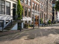 a paved street with parked cars near brick buildings and stairs down the middle of it