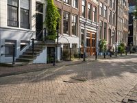 a paved street with parked cars near brick buildings and stairs down the middle of it