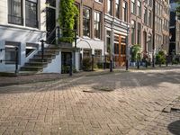 a paved street with parked cars near brick buildings and stairs down the middle of it