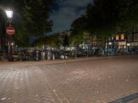 a city square with lots of bicycles parked by the fence and buildings in the background