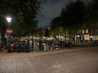 a city square with lots of bicycles parked by the fence and buildings in the background