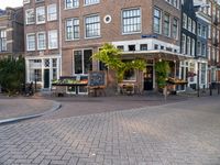 a building that has some tables and chairs on it near a sidewalk by the street