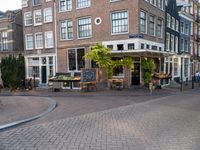 a building that has some tables and chairs on it near a sidewalk by the street