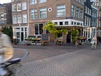 a building that has some tables and chairs on it near a sidewalk by the street