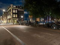 bicycles are parked on the sidewalk by a building in front of trees and buildings in the dark at night