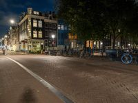 bicycles are parked on the sidewalk by a building in front of trees and buildings in the dark at night