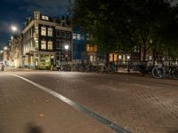 bicycles are parked on the sidewalk by a building in front of trees and buildings in the dark at night